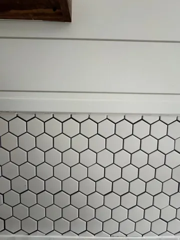 White hexagonal tile backsplash under shiplap wall paneling