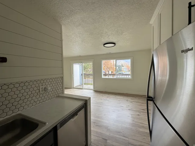 Open-concept living area featuring wood-finish flooring, a contemporary ceiling light fixture, and a sliding glass door leading to an outdoor deck