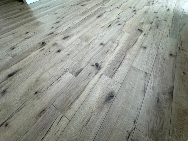 Wide-plank wood-finish flooring with a distressed texture and visible knot details