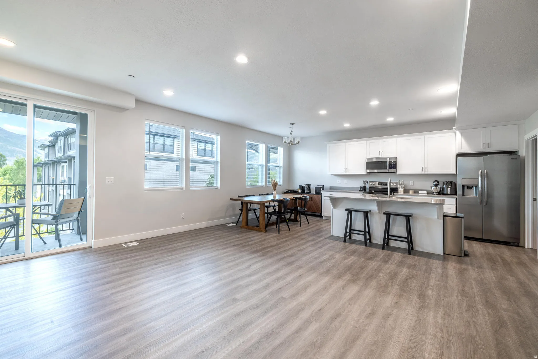 Open-concept living space featuring wood-finish flooring, recessed lighting, and multiple windows for abundant natural light