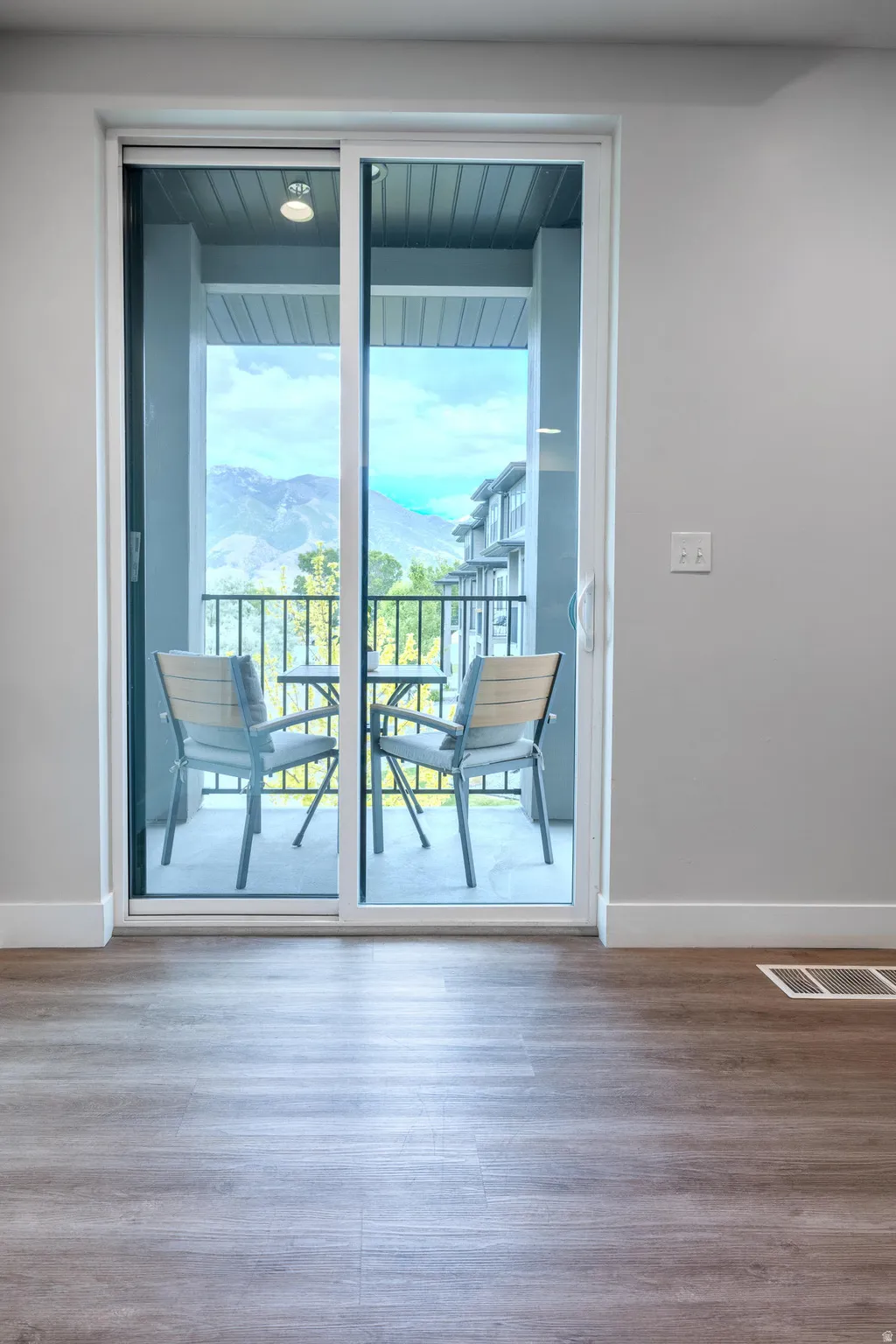 Sliding glass door opens to an outdoor balcony with mountain scenery