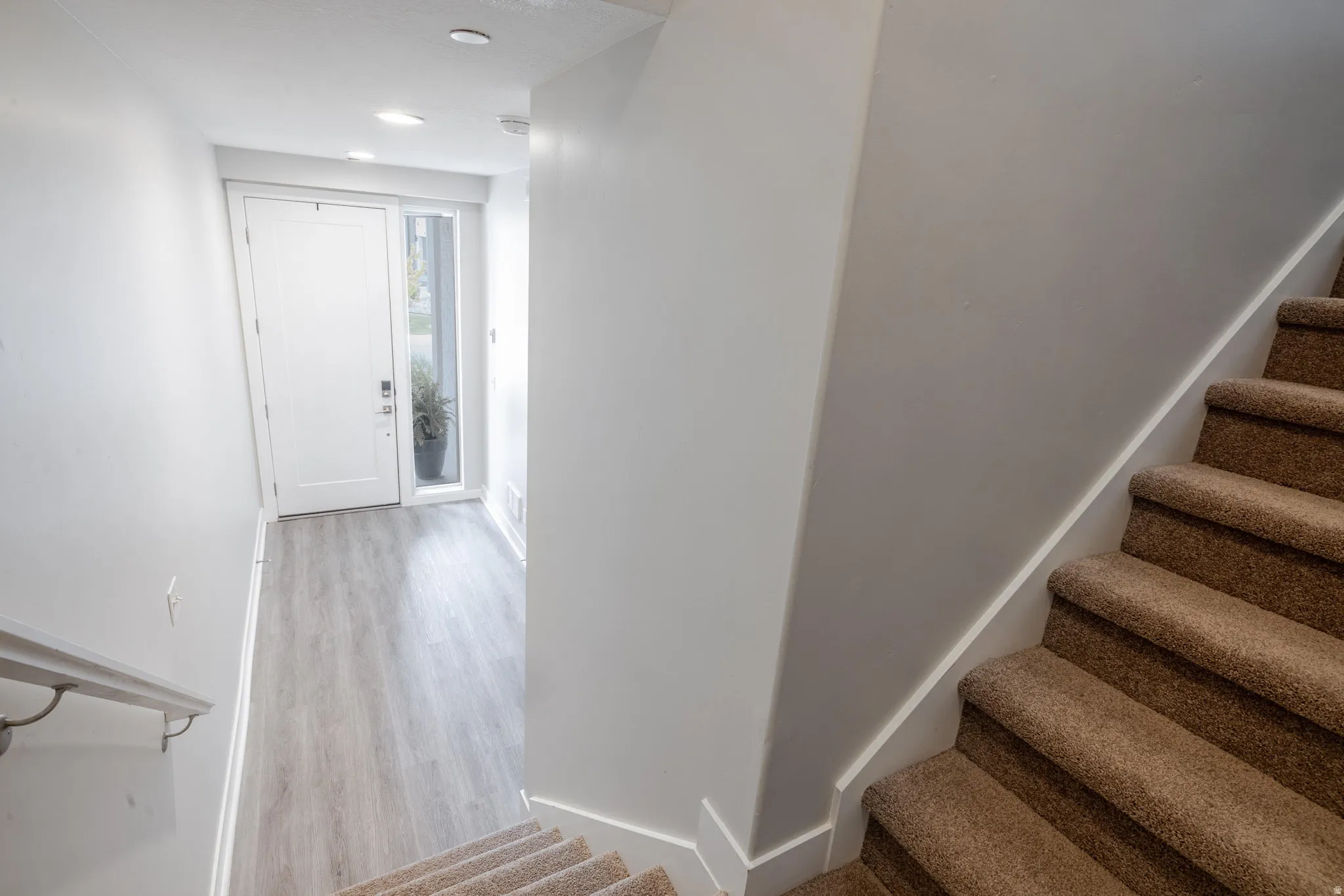 Entryway featuring a white door with a tall side light, wood-finish flooring, and recessed ceiling lighting