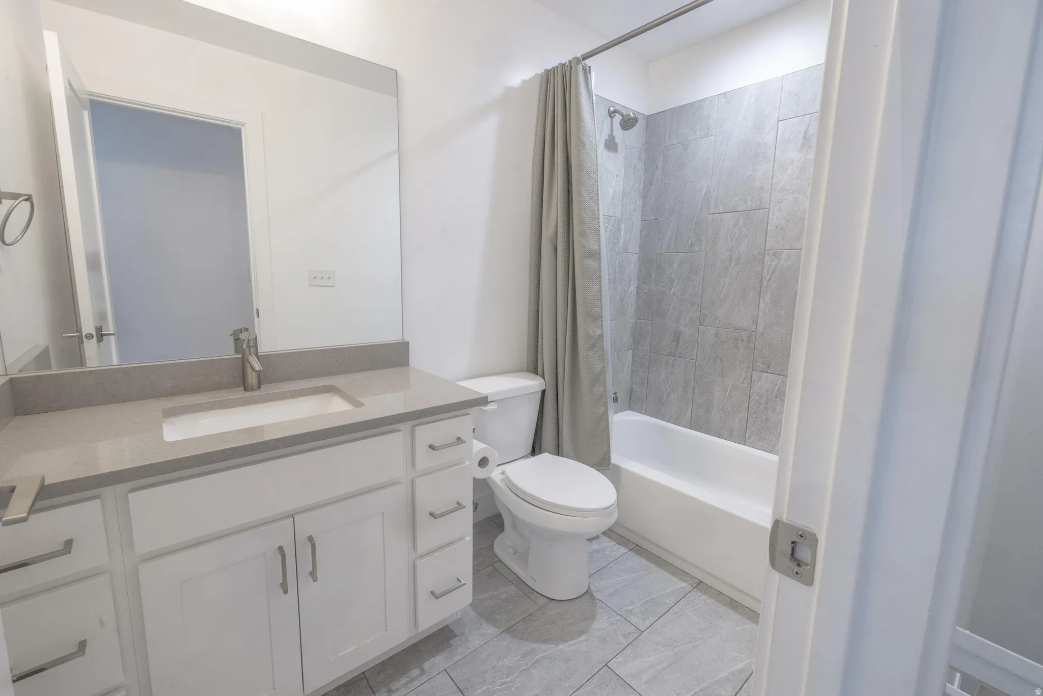 Bathroom featuring a white vanity with a stone-finish countertop, undermount sink, and chrome faucet