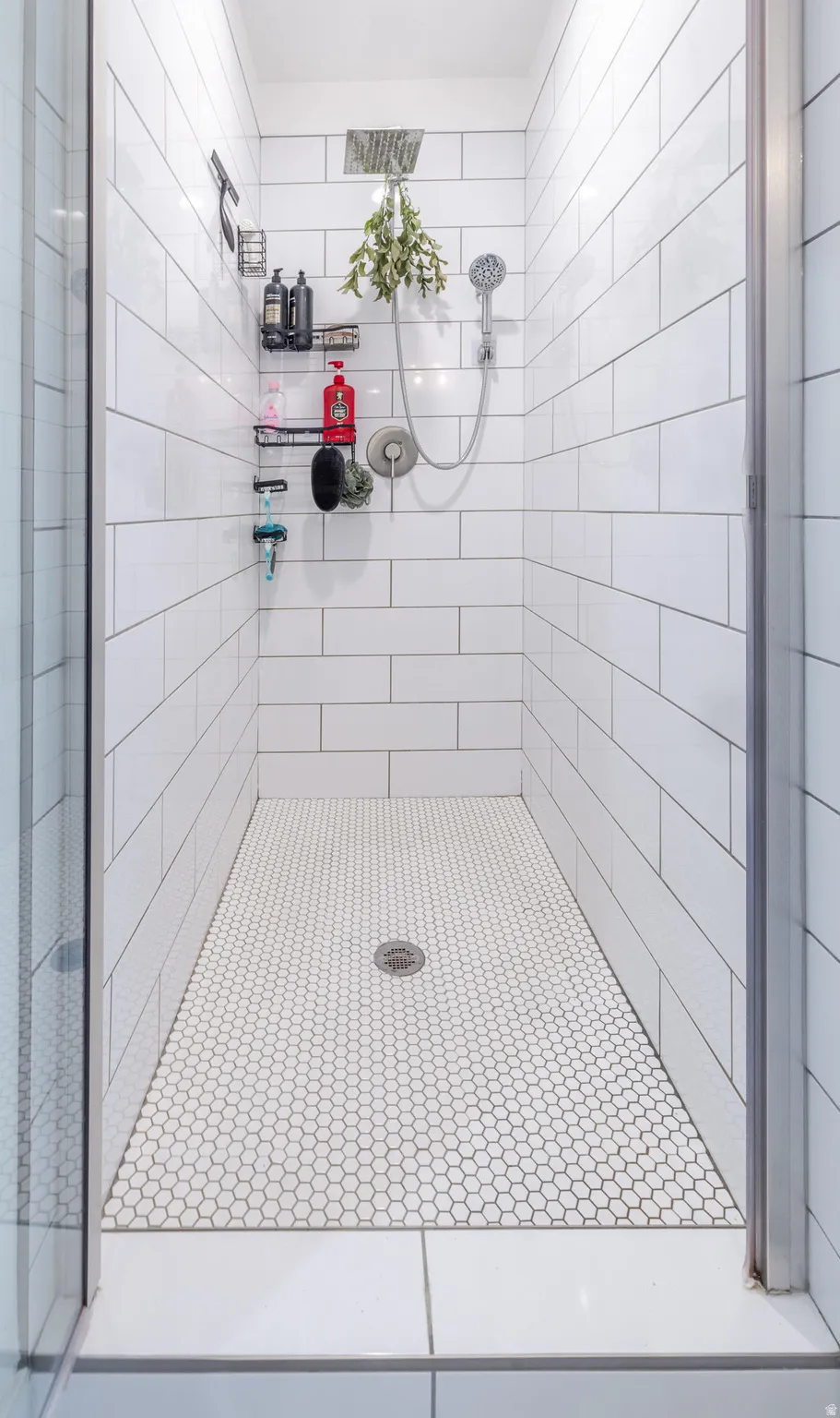 Walk-in shower featuring white subway tile walls and a hexagonal mosaic tile floor