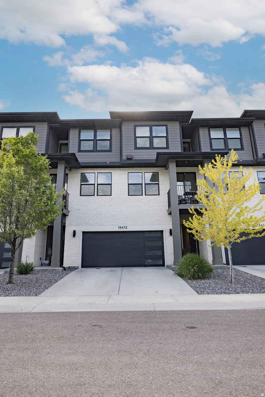Modern townhome exterior featuring a white brick facade and dark siding accents