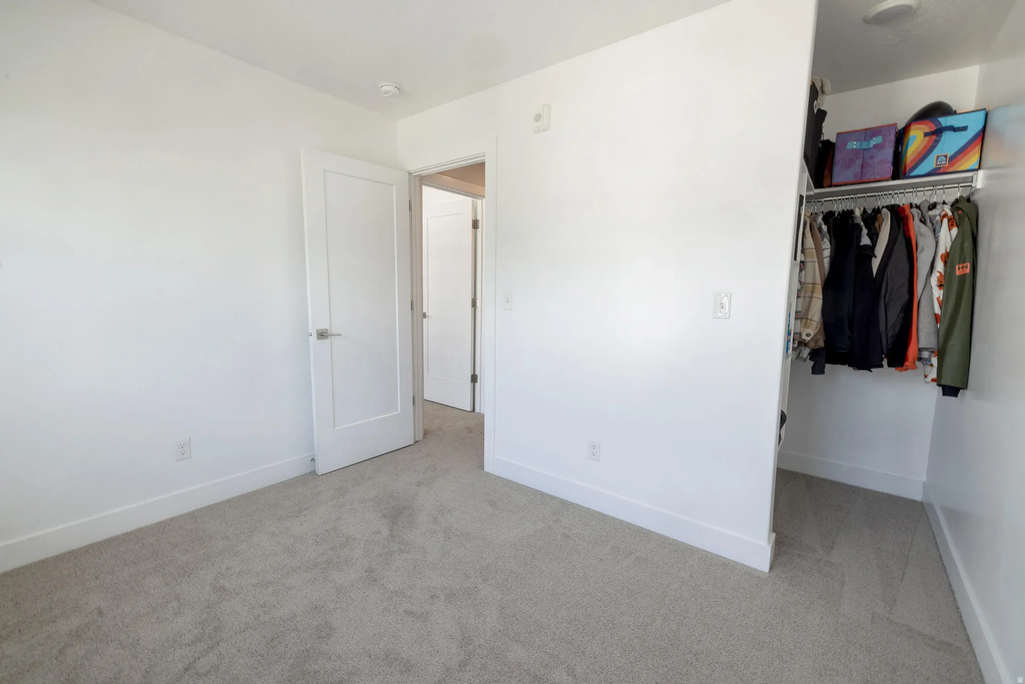 Minimalist interior featuring light-colored carpeting, white baseboards, and a neutral wall palette