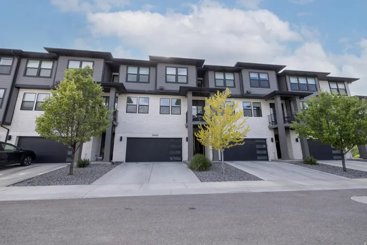 Contemporary multi-story townhome with a mixed material facade featuring white brick and dark horizontal siding
