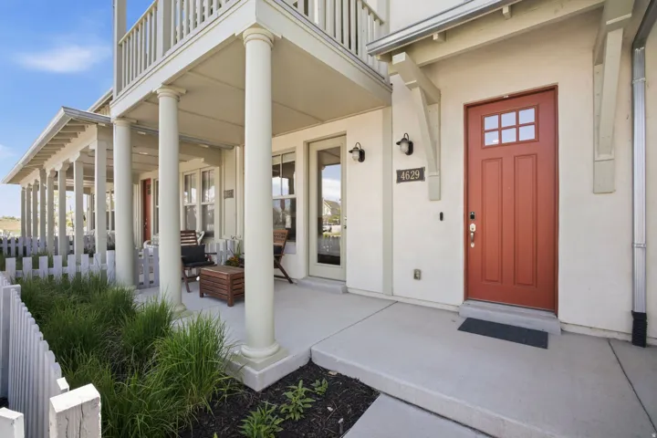 Front facade featuring a red paneled main entry door and a covered porch off the main-level bedroom