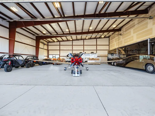Spacious hangar building featuring a concrete floor, high ceilings with exposed steel beams, and a large overhead door