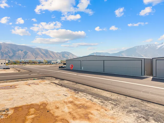 Industrial building with corrugated metal siding, large sliding bay doors, and a paved runway