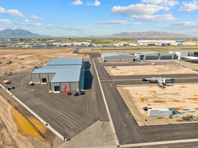 Expansive industrial property featuring a paved tarmac and multiple hangar-style buildings with metal siding and roofs