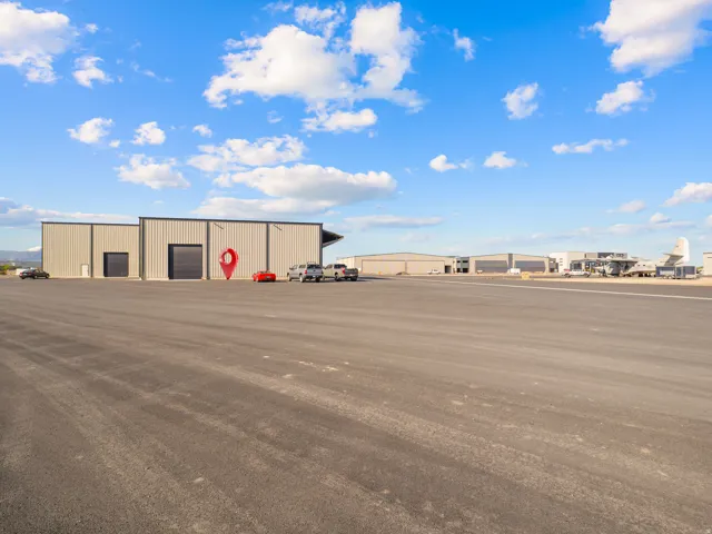 Expansive paved lot with a large industrial building featuring multiple bay doors and a light gray metal exterior