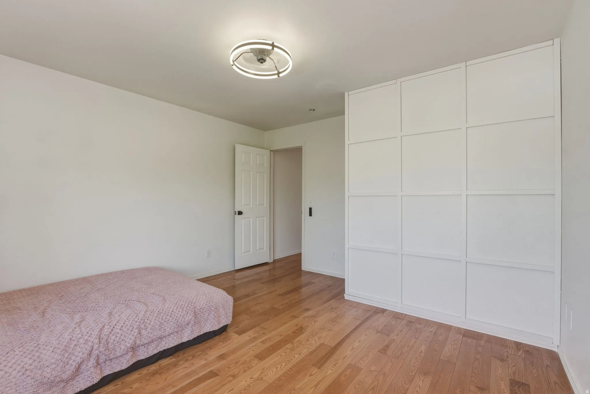 Spacious room featuring wood-finish flooring and a white paneled built-in wardrobe