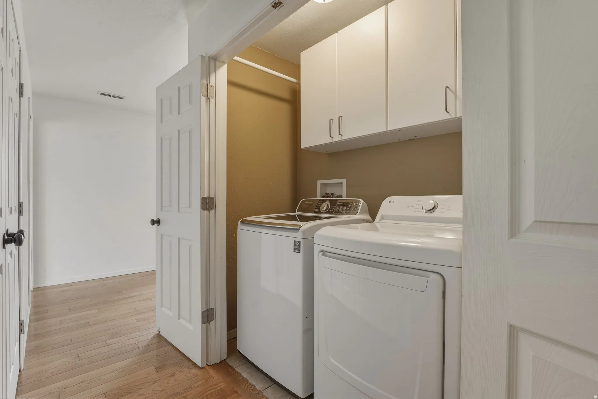 Dedicated laundry area featuring white upper cabinetry, a utility sink hookup, and neutral wall tones
