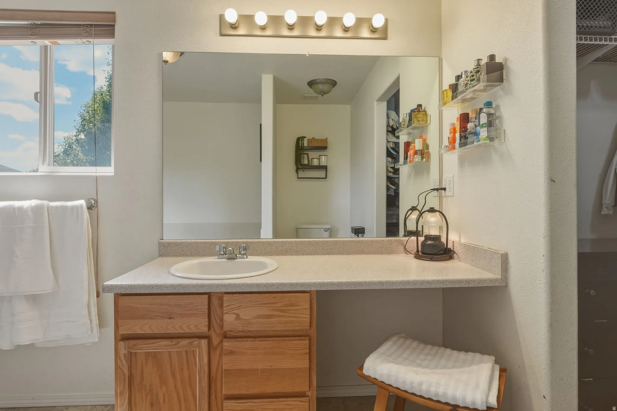 Bathroom vanity with wood-finish cabinetry, a drop-in sink, and a light-colored countertop