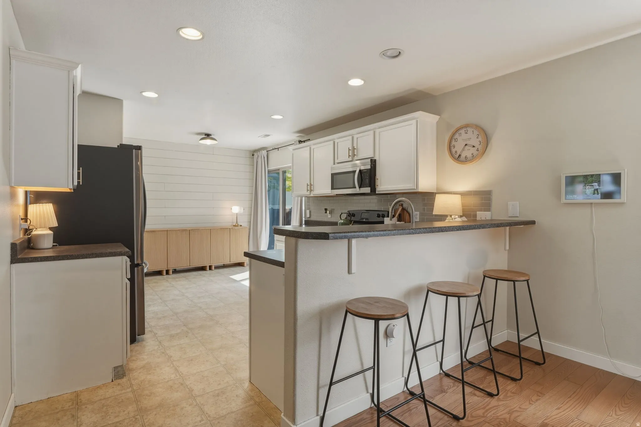 Kitchen with white cabinetry, stainless steel microwave, and gray countertops