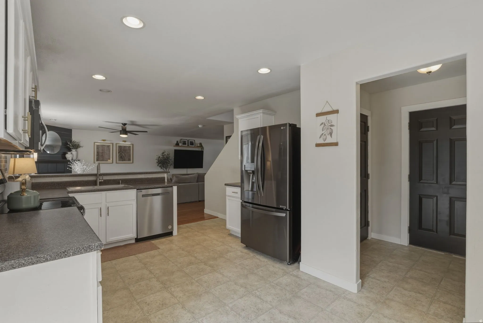 Kitchen featuring tile flooring, white cabinetry, dark speckled countertops, and stainless steel appliances