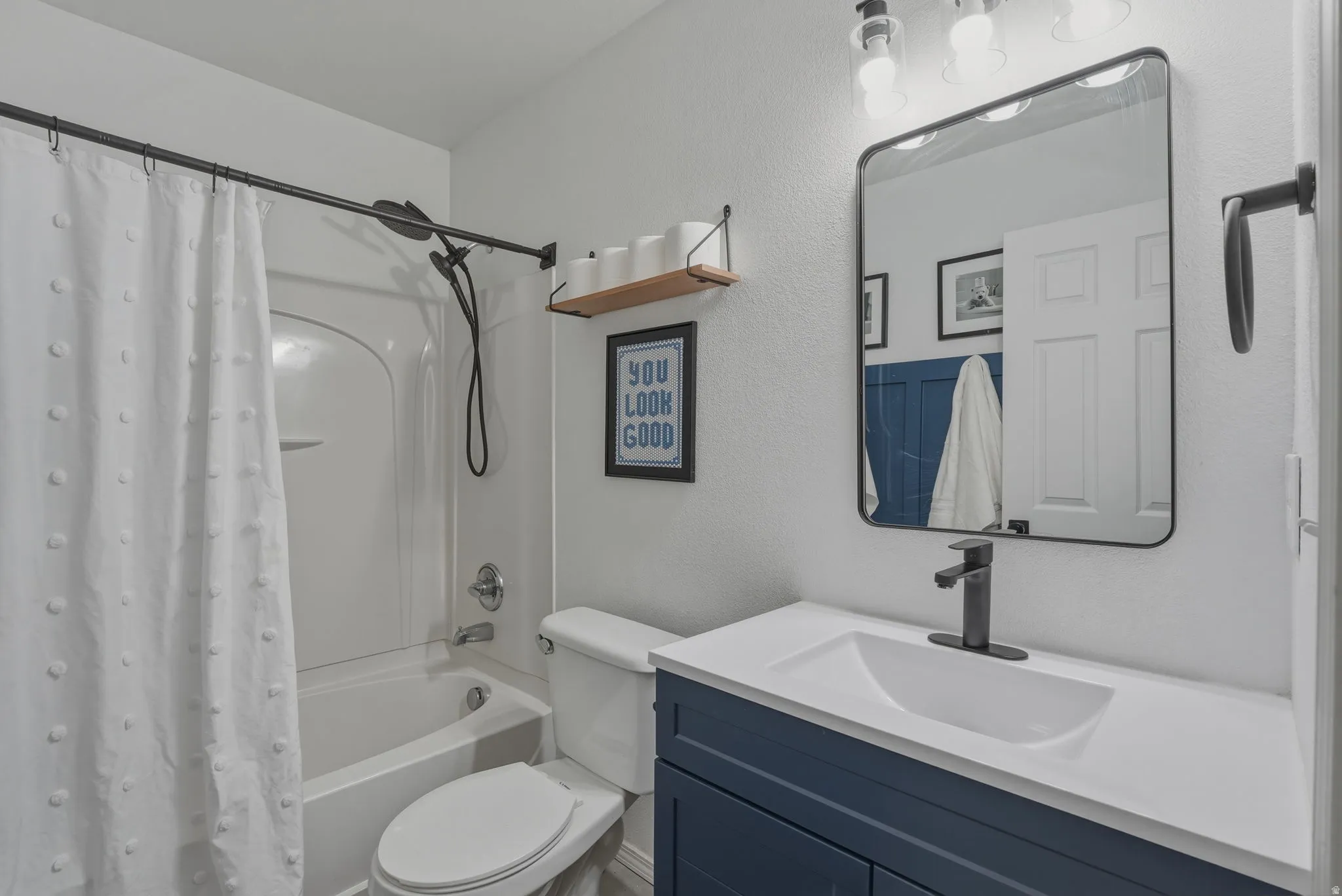 Bathroom featuring a dark blue vanity, white countertop with integrated sink, and matte black faucet