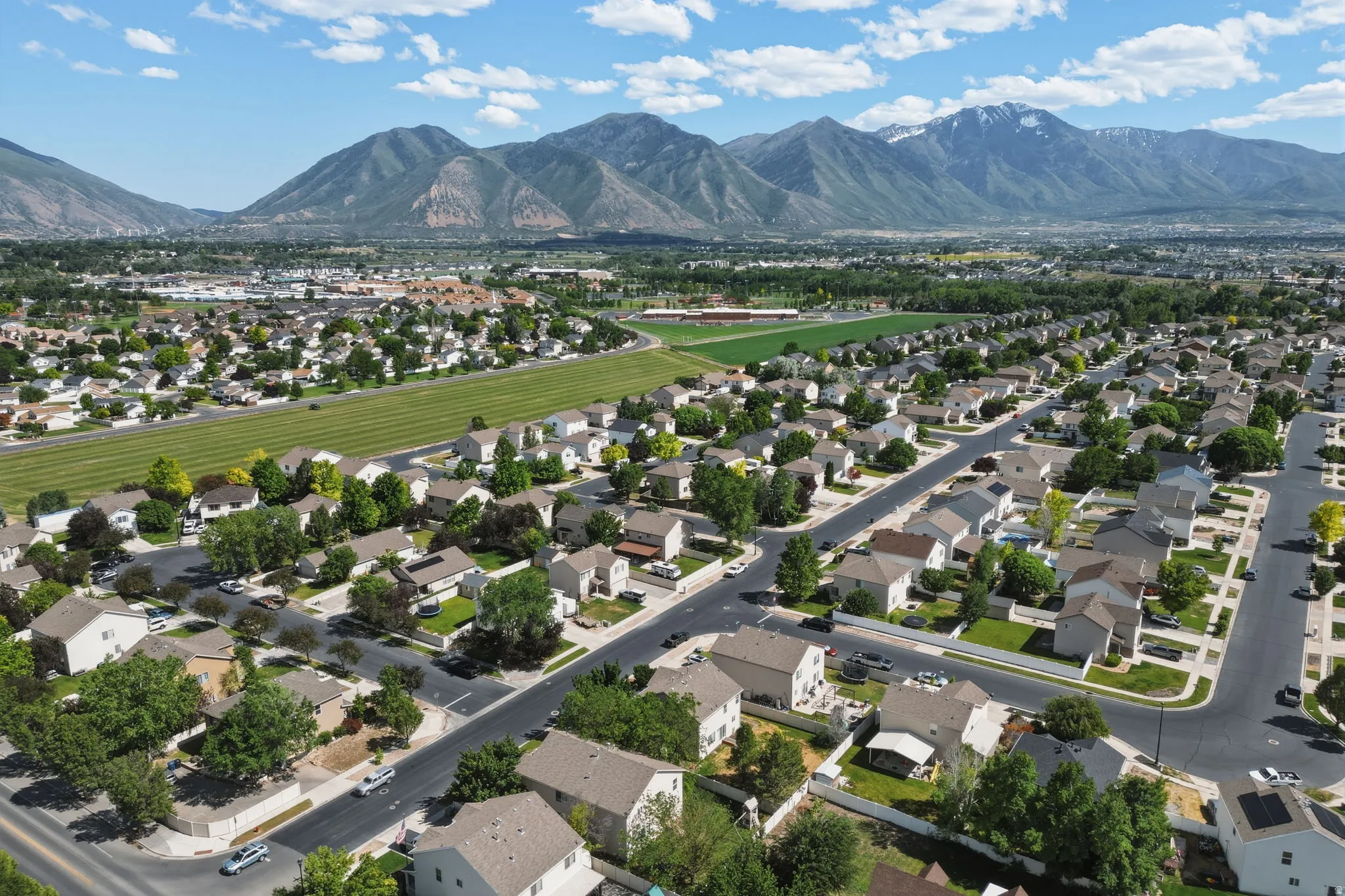 Expansive aerial showcasing a residential neighborhood with detached homes, mature trees, and paved roads