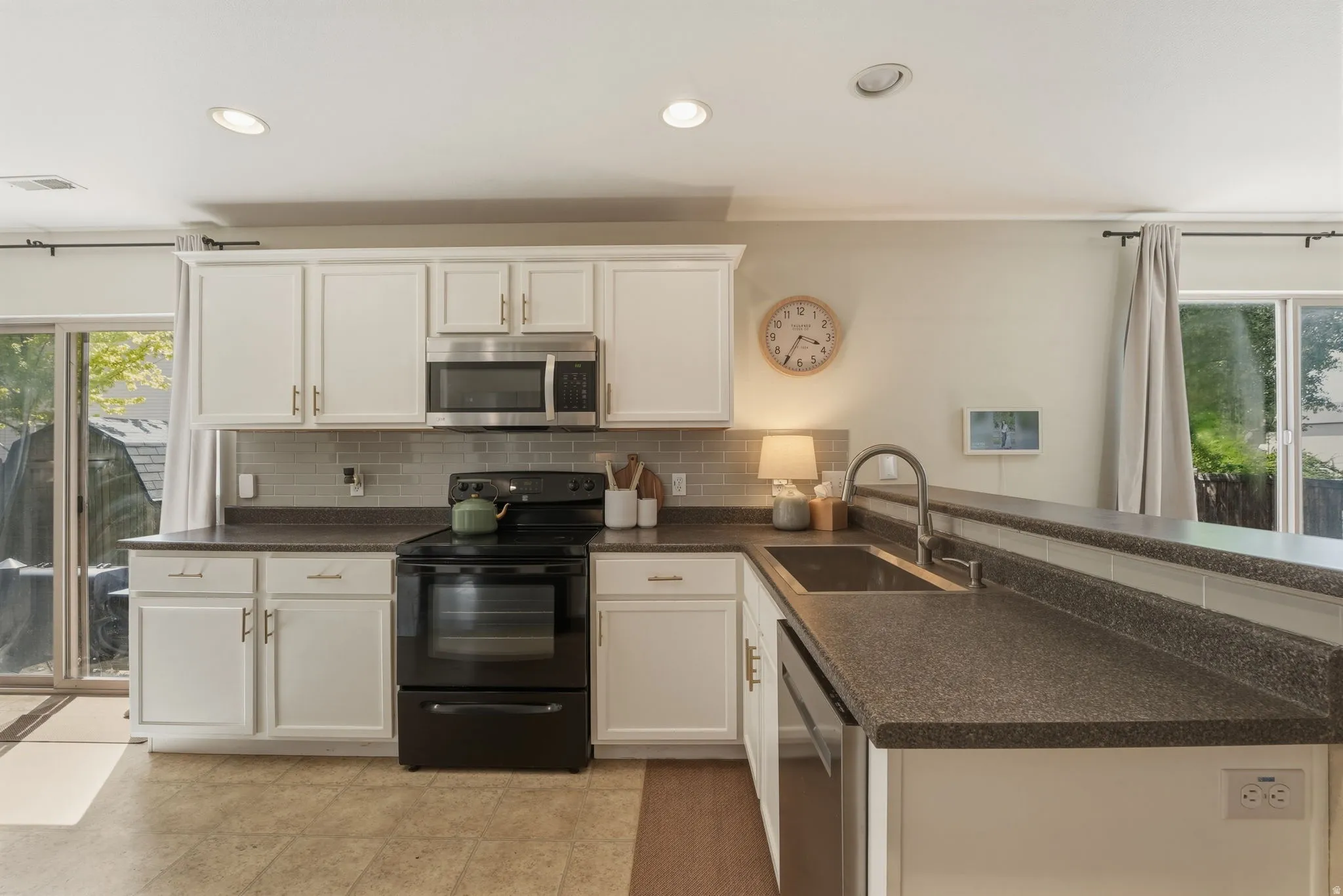 Kitchen featuring white cabinetry, dark countertops, and stainless steel appliances