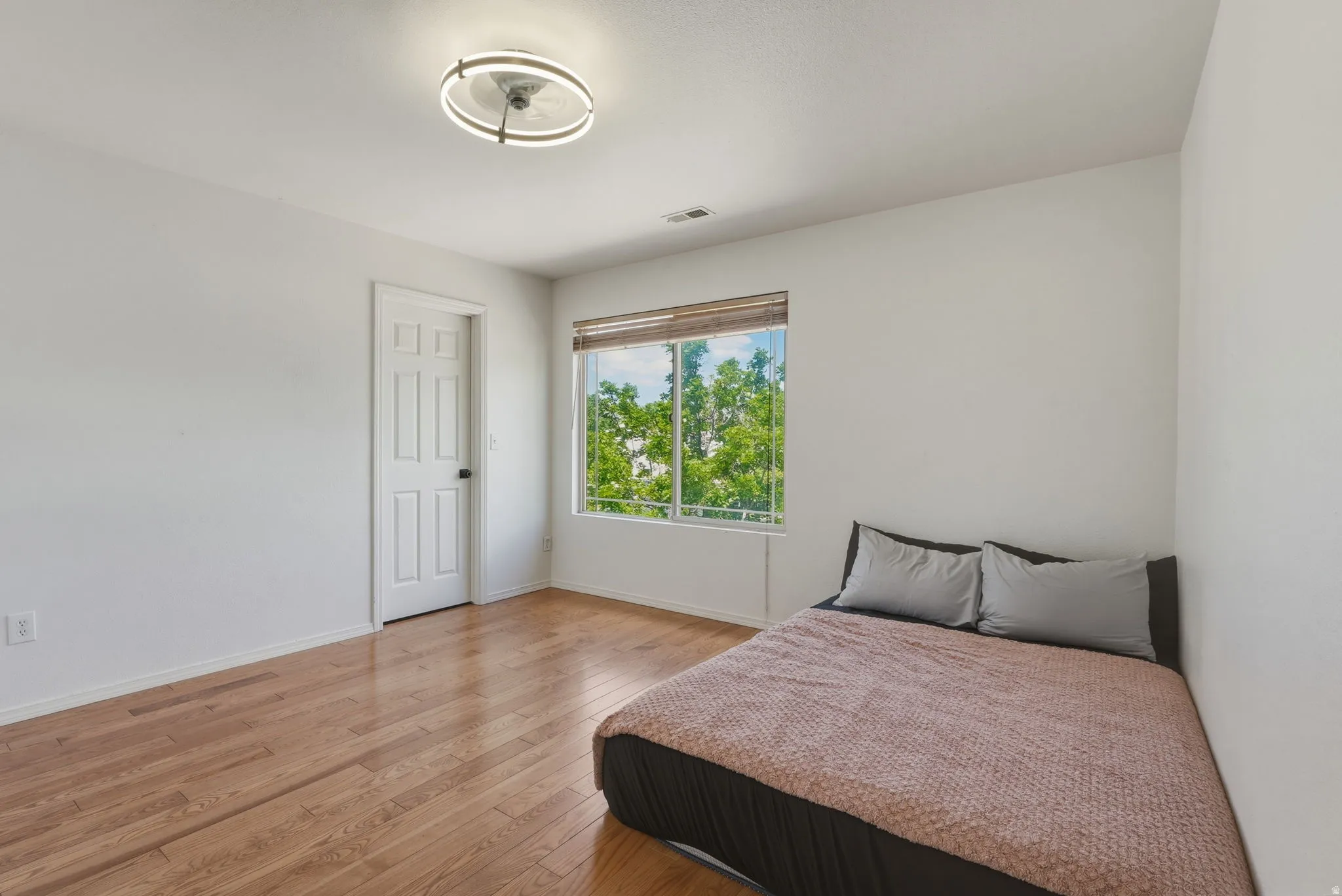 Hardwood flooring extends throughout this bedroom, complemented by a contemporary flush mount ceiling light