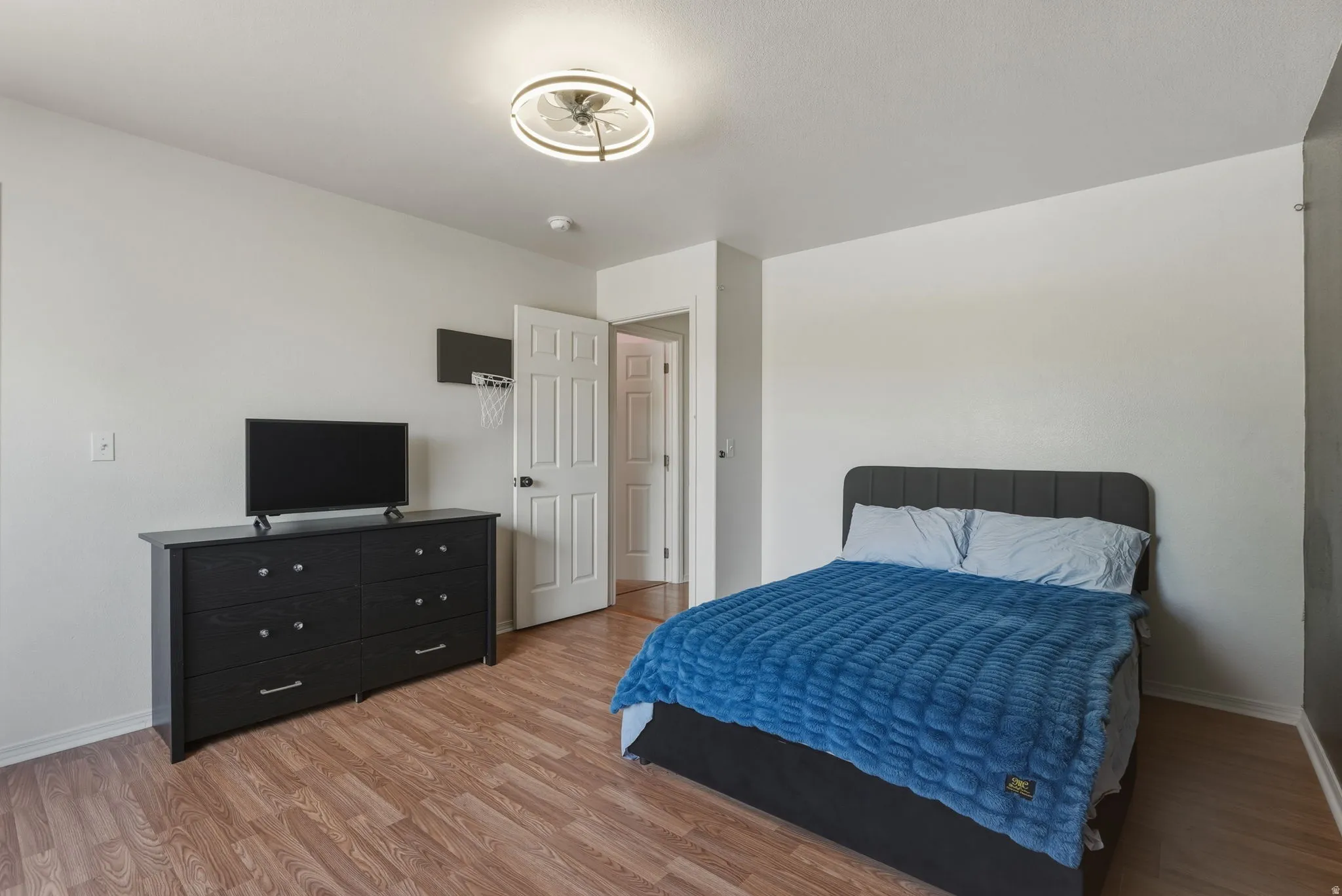 Bedroom featuring wood-finish flooring, white walls, and a modern ceiling light fixture