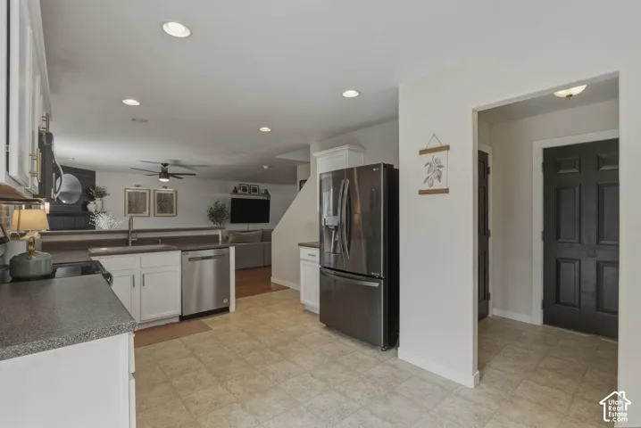 Kitchen featuring tile flooring, white cabinetry, dark speckled countertops, and stainless steel appliances