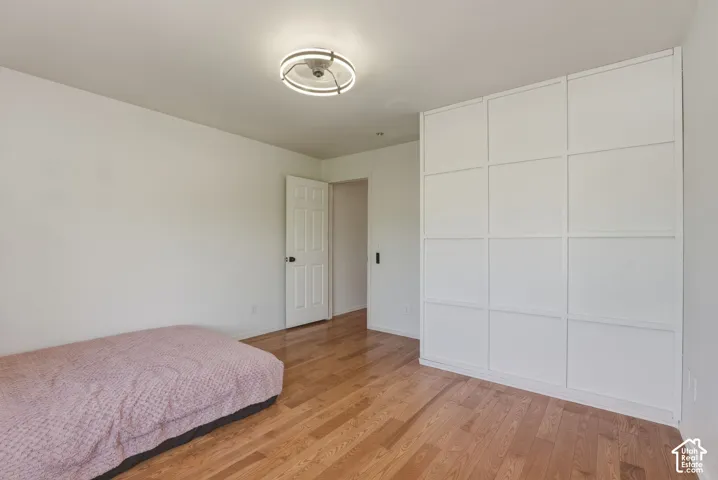 Spacious room featuring wood-finish flooring and a white paneled built-in wardrobe