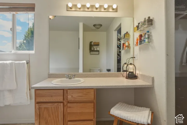 Bathroom vanity with wood-finish cabinetry, a drop-in sink, and a light-colored countertop