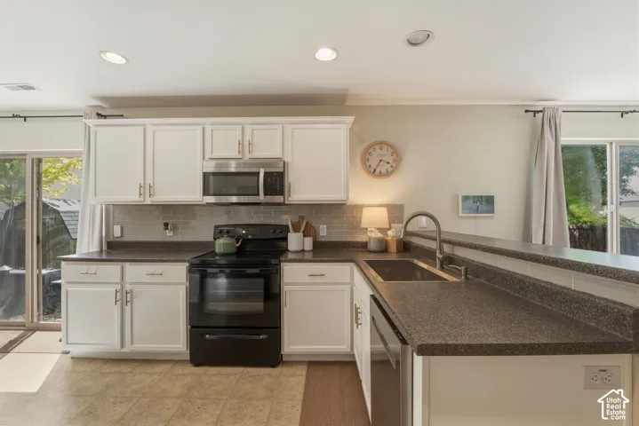 Kitchen featuring white cabinetry, dark countertops, and stainless steel appliances
