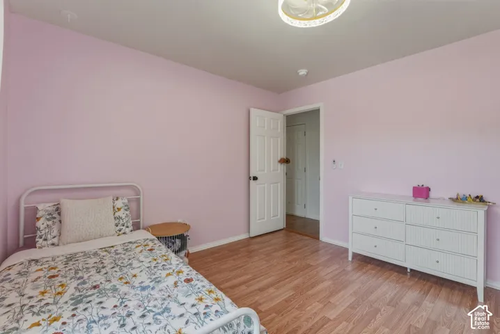 Interior room featuring wood-finish flooring, a white paneled door, and a built-in closet visible through the doorway