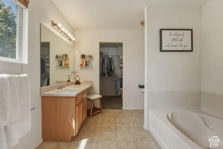Spacious bathroom featuring a light wood-finish vanity with an integrated sink, a large wall-mounted mirror, and overhead lighting