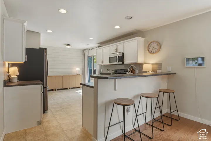 Kitchen with white cabinetry, stainless steel microwave, and gray countertops