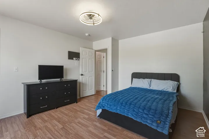 Bedroom featuring wood-finish flooring, white walls, and a modern ceiling light fixture