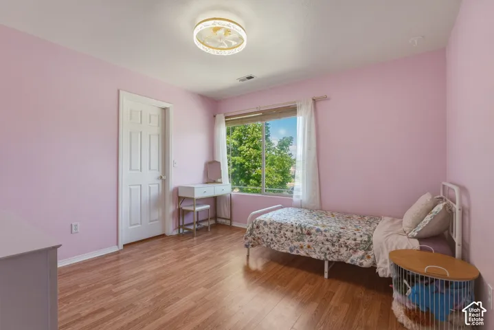 Room featuring wood-finish flooring, a multi-pane window with white sheers, and a five-panel interior door