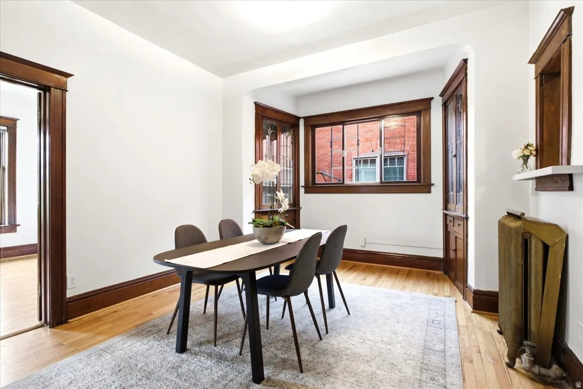 Dining area featuring hardwood flooring, white walls, dark wood trim, large windows with dark wood frames, and a built-in shelf