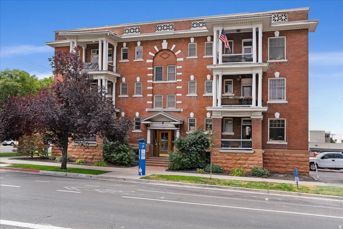 Brick exterior building featuring multiple balconies, decorative white trim, arched entryway, and stone foundation