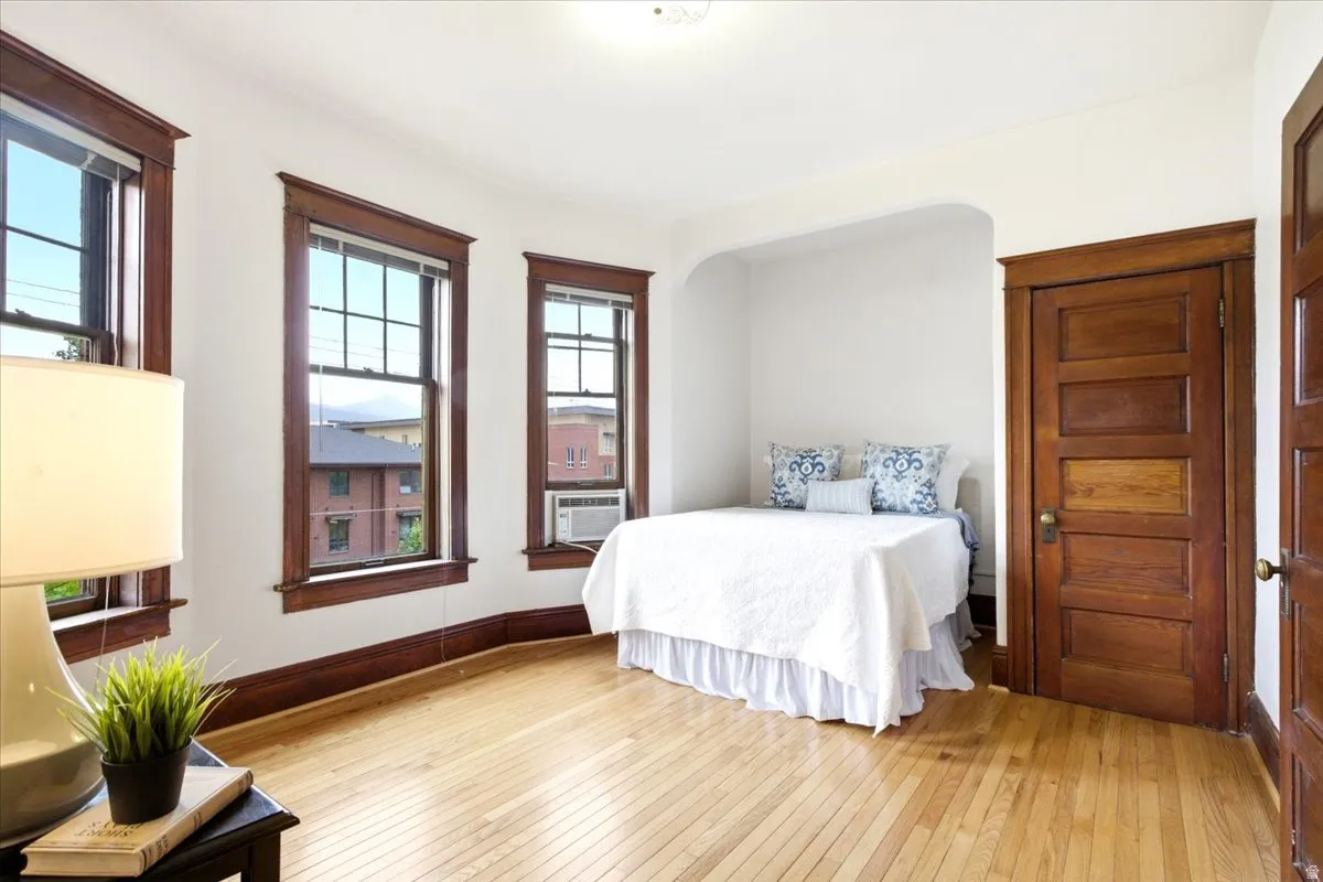 Hardwood flooring and white walls define this room, featuring three windows with dark wood trim