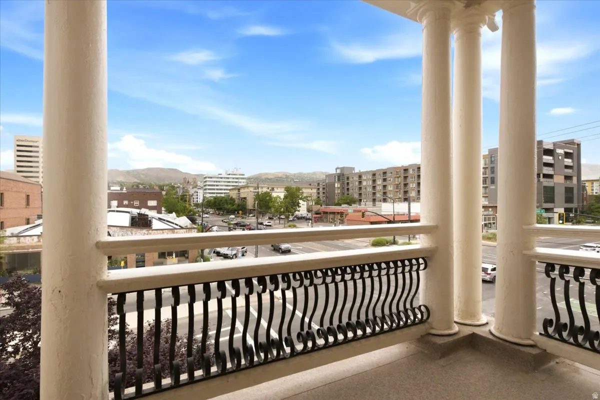 Balcony with classical columns, ornate black wrought iron railing, and a textured concrete floor