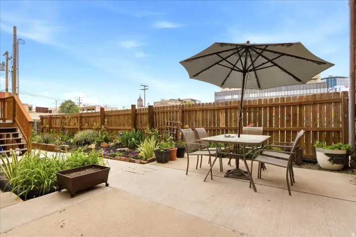 Patio area featuring concrete surfacing, a wooden privacy fence, raised garden beds with established plantings, and a wooden exterior staircase