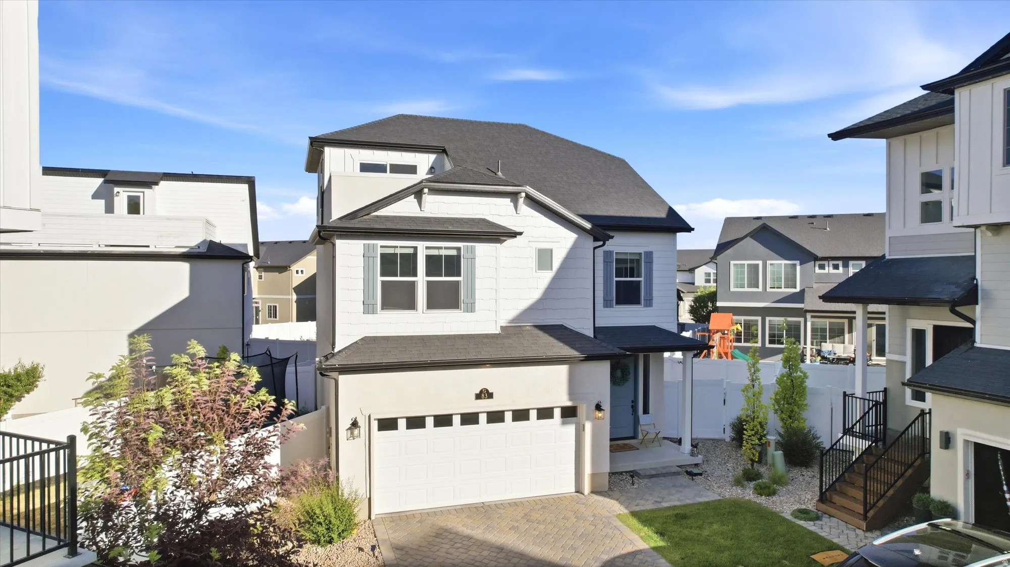 Contemporary two-story residence featuring a two-car garage, light-toned siding, and a dark shingle roof