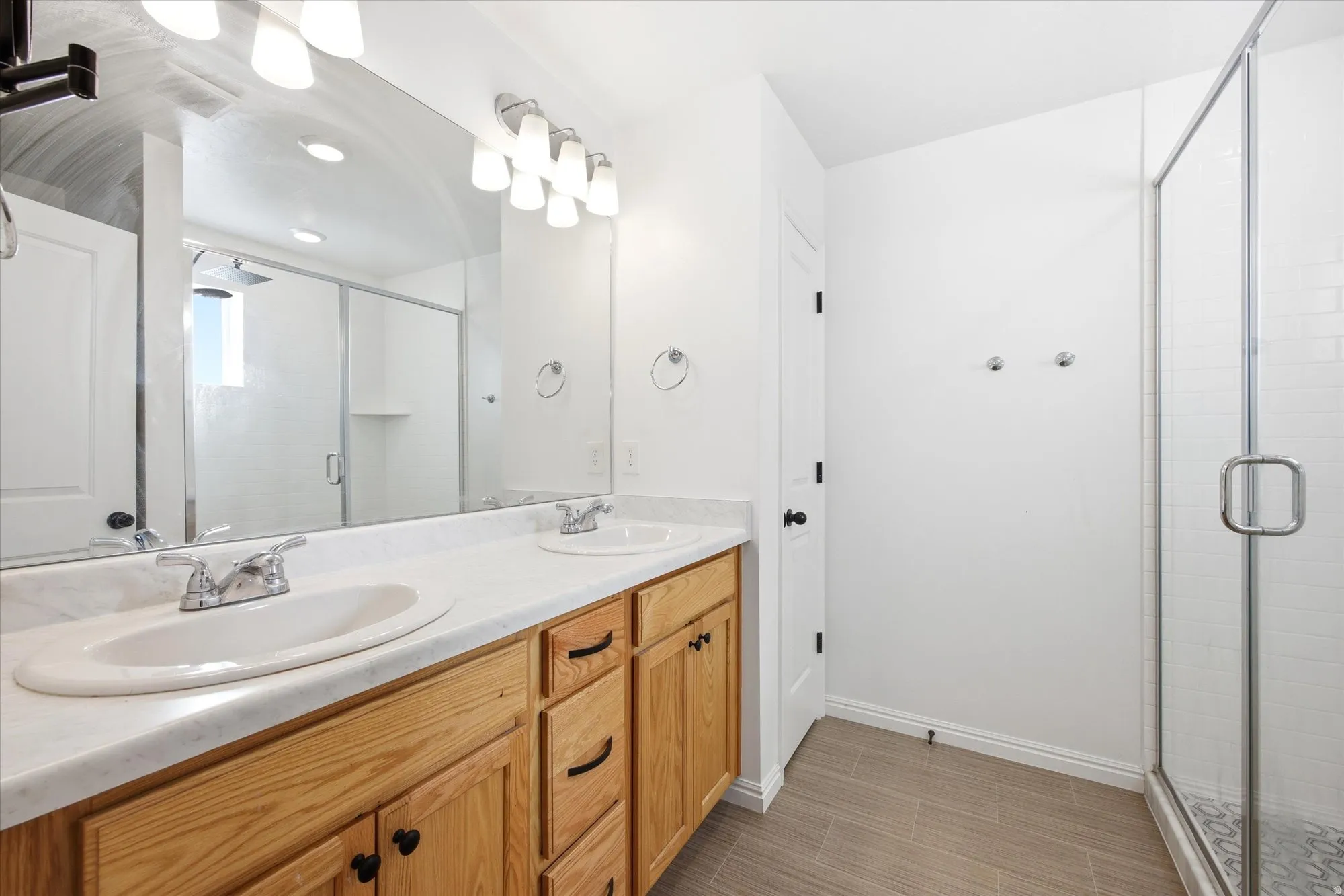 Dual vanity featuring wood cabinetry, white countertops, and chrome fixtures
