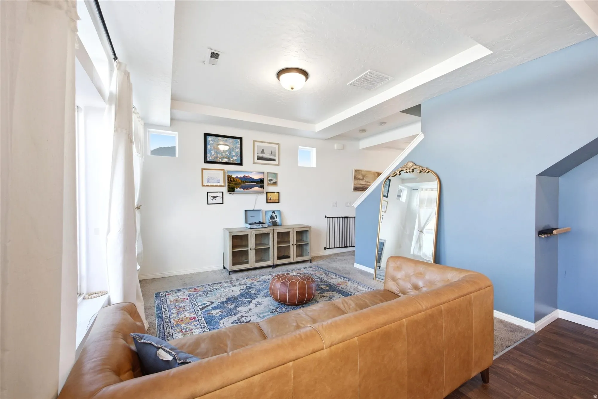 Bright living space featuring high ceilings, a wall of windows, wood-finish flooring, and a built-in media console