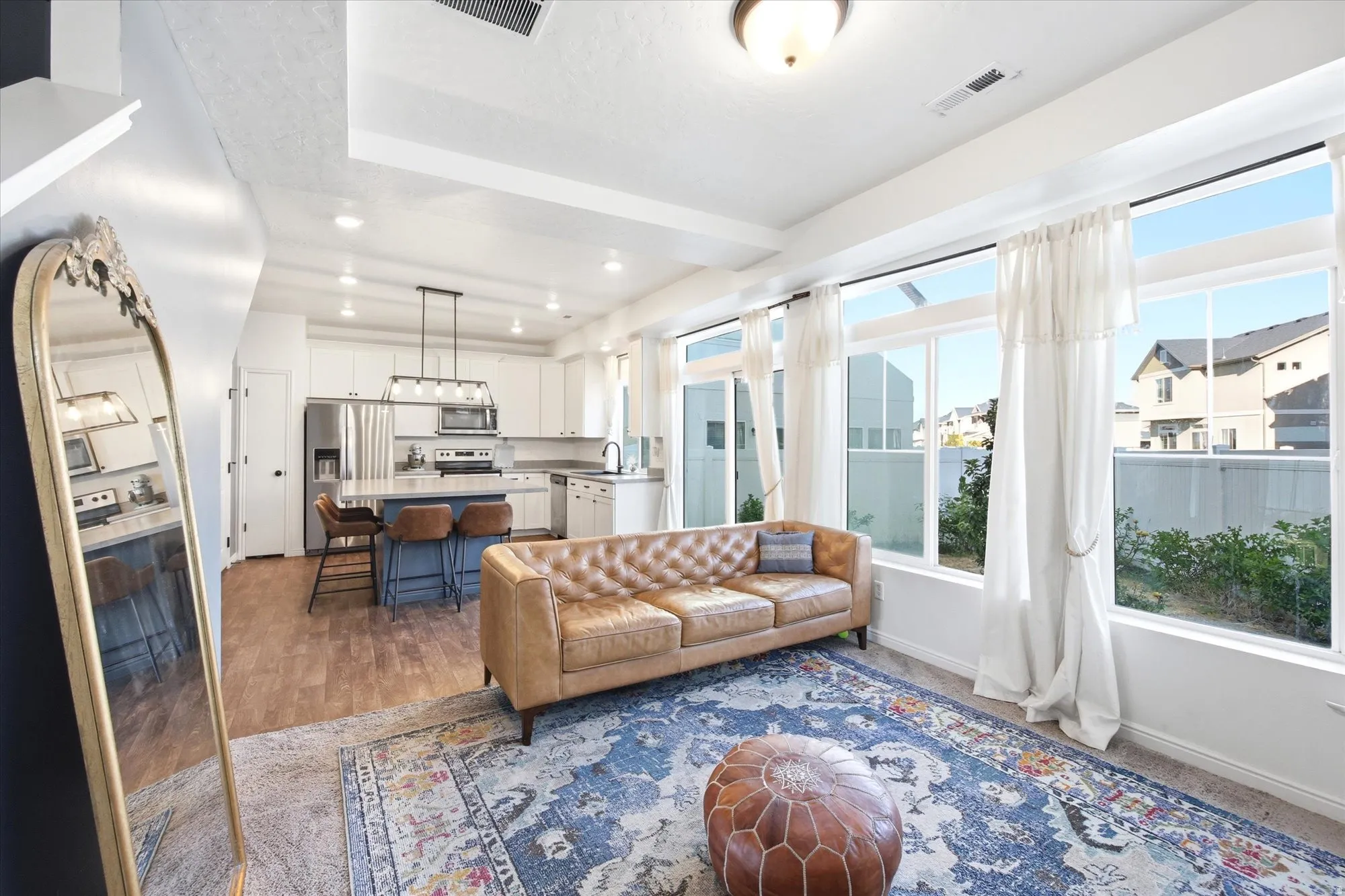 Open-concept living space featuring wood-finish flooring, recessed lighting, and a kitchen with white cabinetry