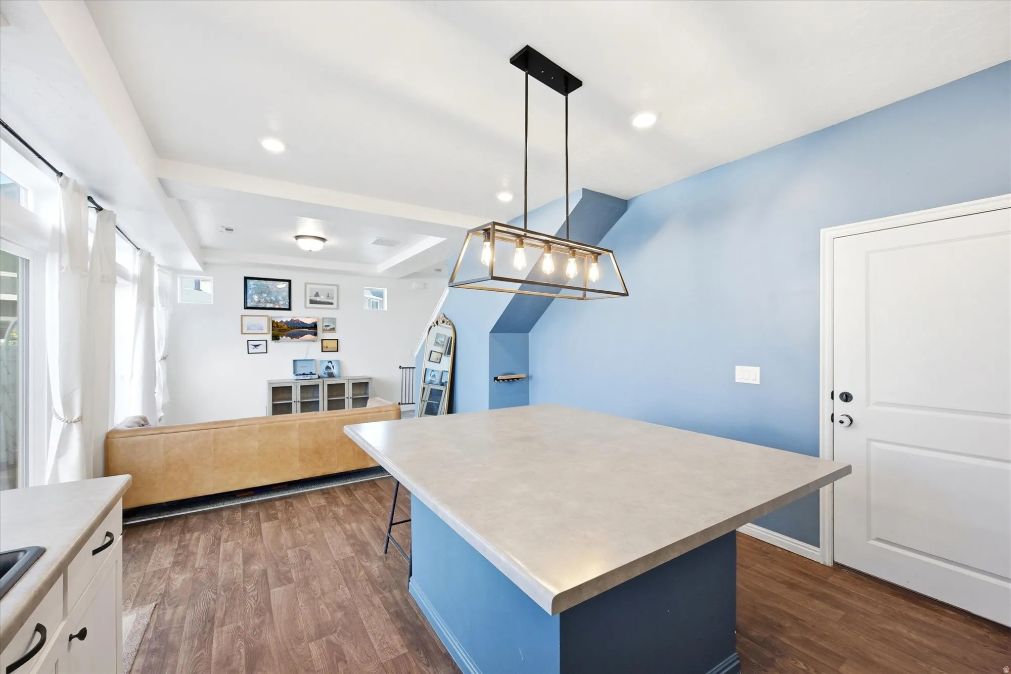 Kitchen island with a light-colored countertop and a blue base, complemented by a linear chandelier