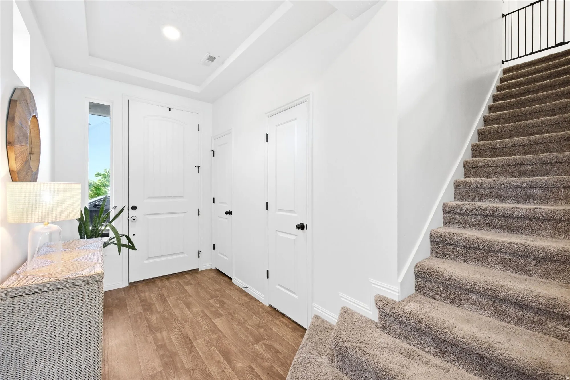 Entryway featuring wood-finish flooring, a white paneled front door with sidelight, and a tray ceiling with recessed lighting