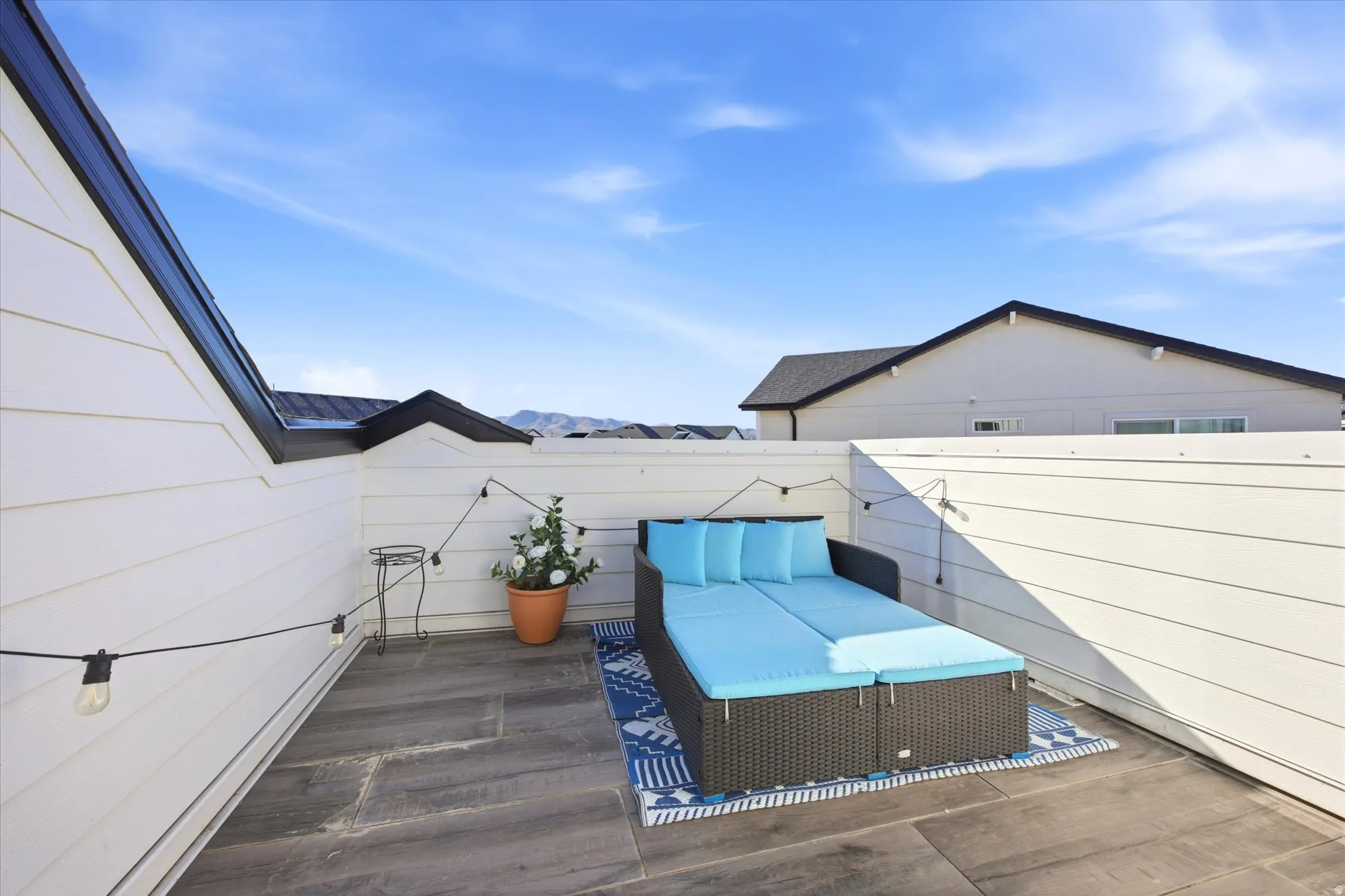 Rooftop deck featuring plank-style flooring and perimeter string lighting