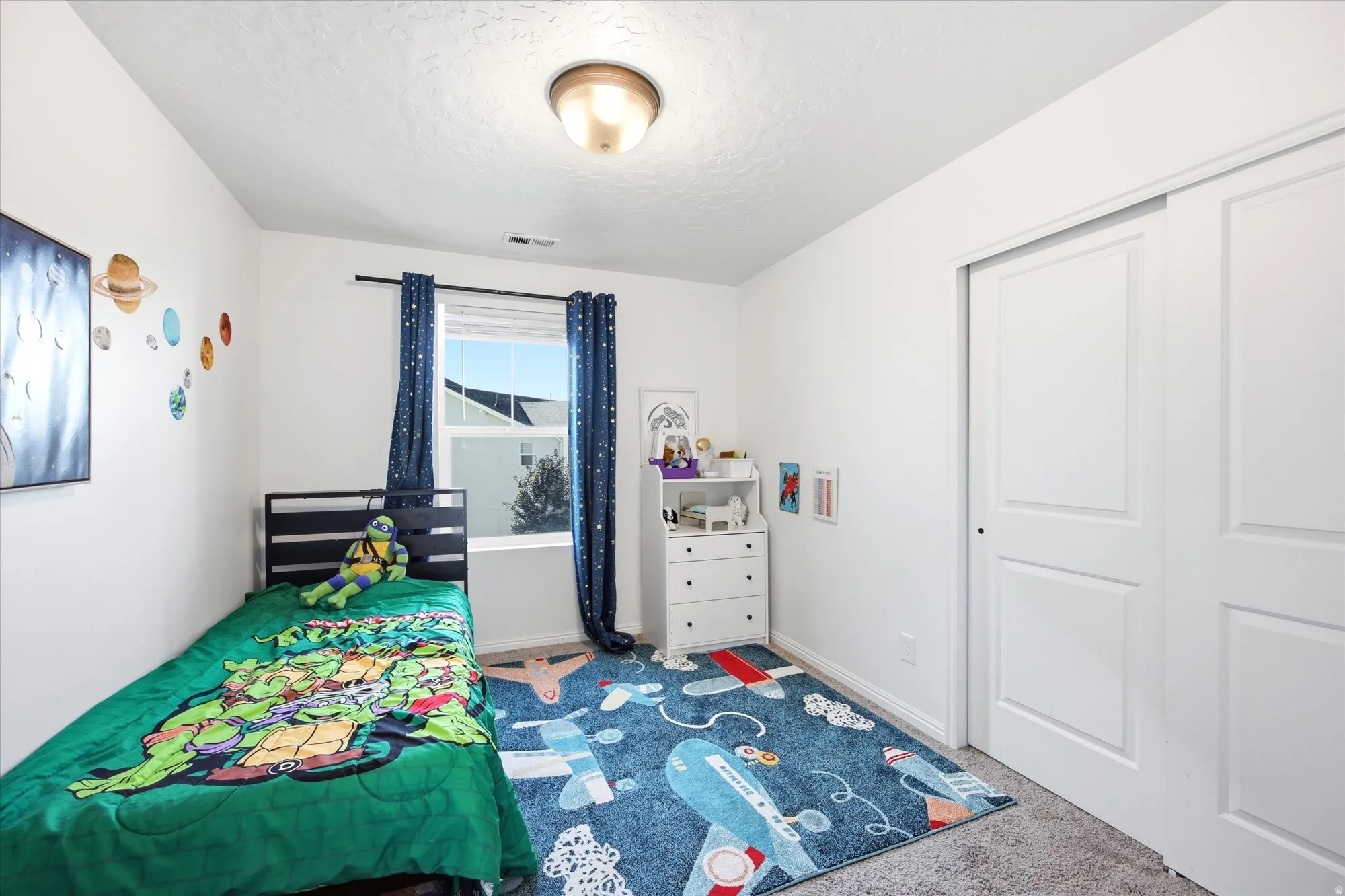 Bedroom featuring a standard window, sliding closet doors, ceiling-mounted light fixture, and carpeted flooring