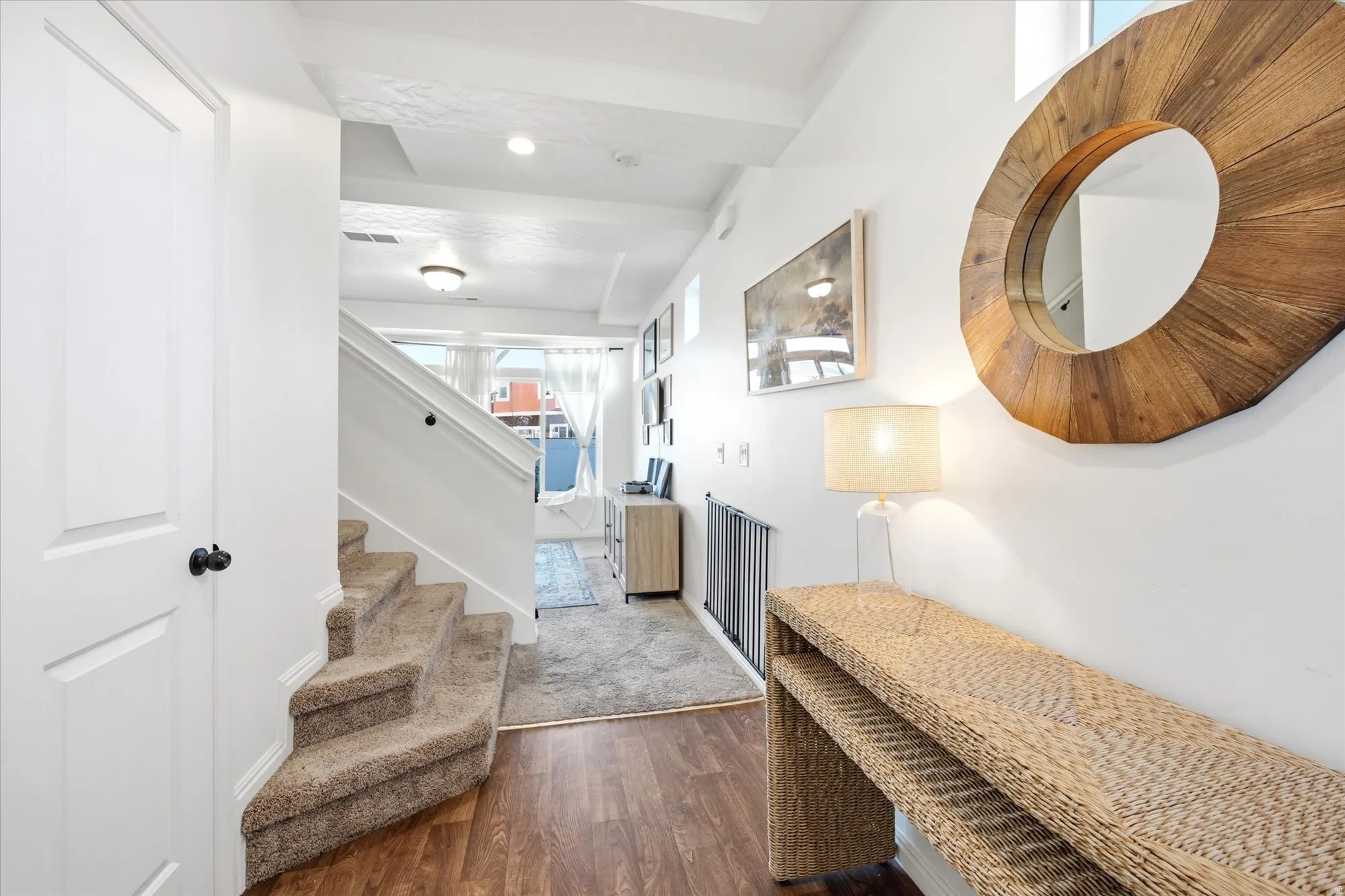 Entryway featuring wood-finish flooring, white trim, and a carpeted staircase with white railings