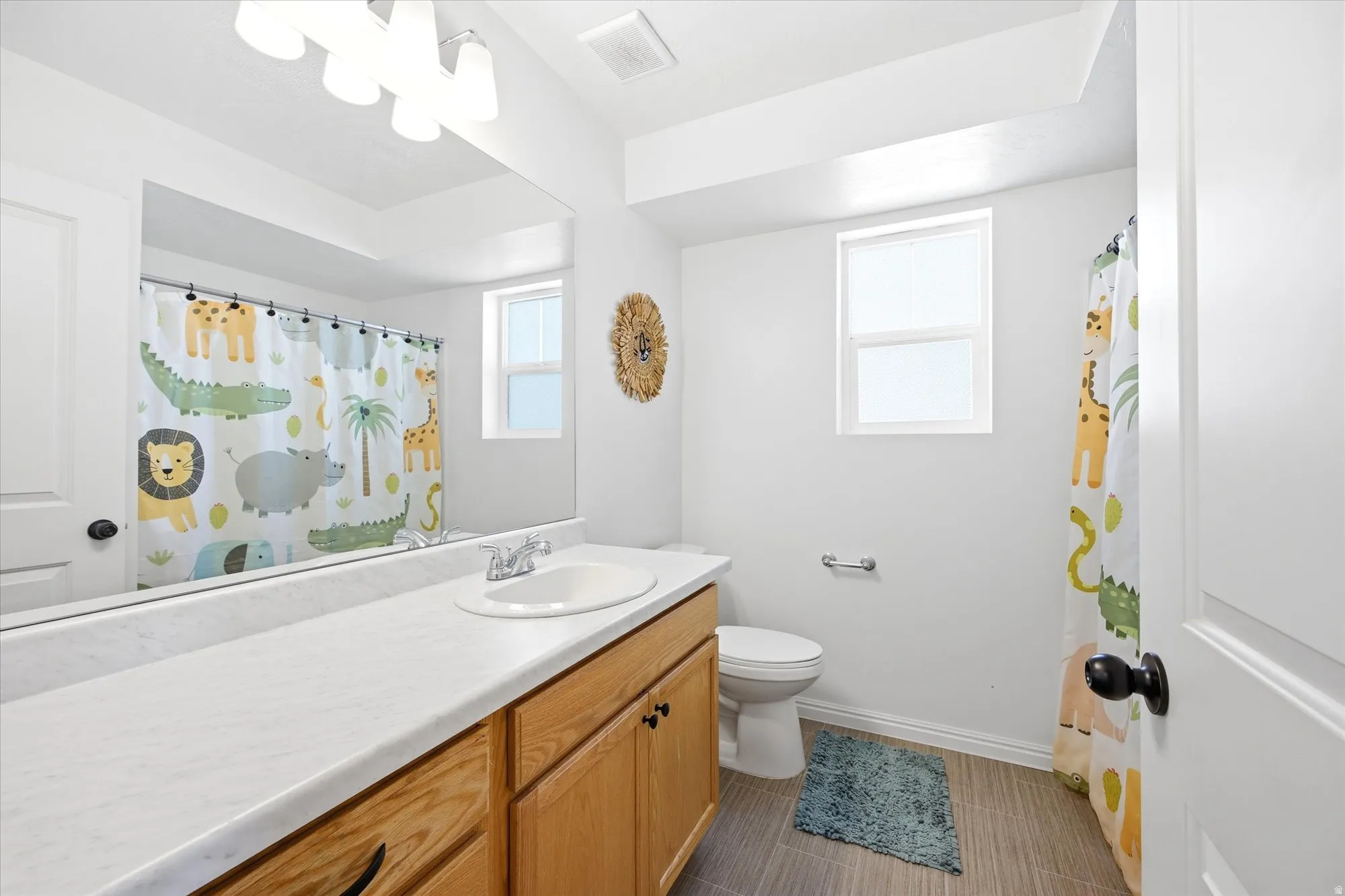 Bathroom vanity with a single sink, light wood cabinetry, and a white countertop